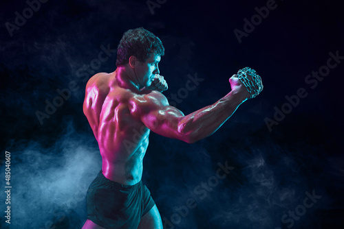 Side view of Muscular fighter who delivering hit with chain on smoke background. mixed media