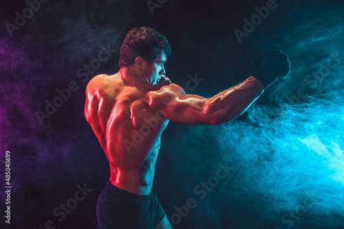 Side view of athlete shirtless boxer who delivering hit jab on smoke background. Sport concept