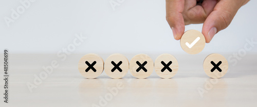 Hand choose check mark on wooden toy stack with cross symbol for true or false changing mindset or way of adapting to change leader and transform quiz answer and poll concept photo