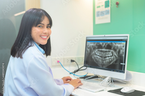 Female dentist working with teeth x-ray on laptop in dental clinic, teeth check-up and Healthy teeth concept