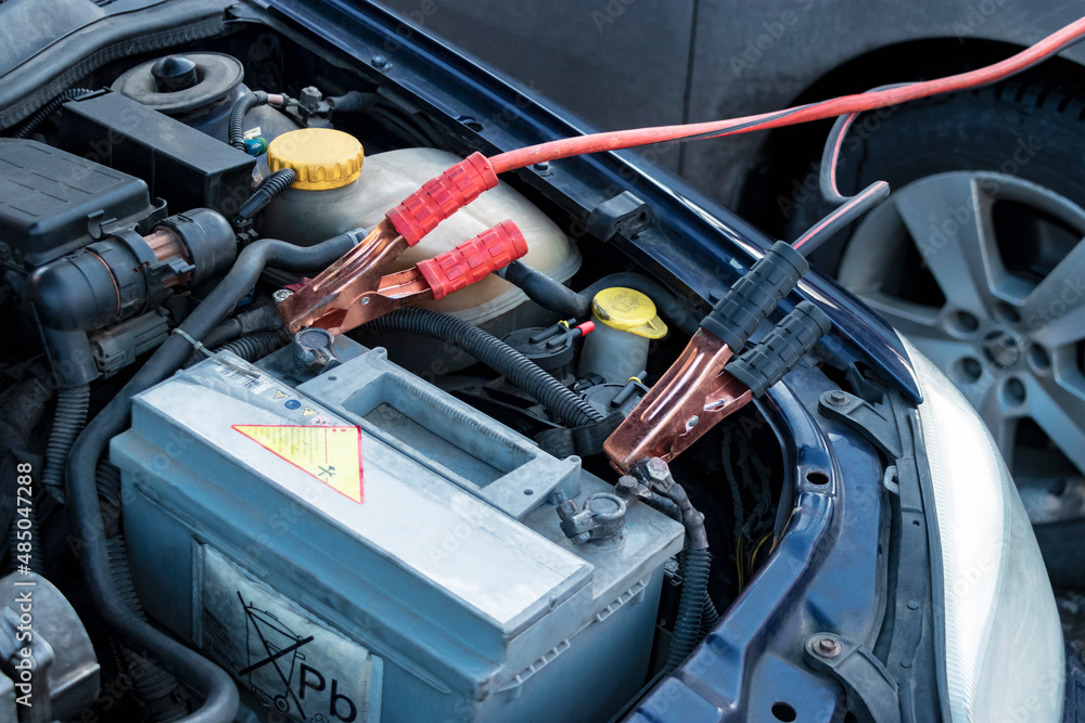 Charging a car battery in winter. Help on the road. Close-up. Connecting high voltage wires to the car battery. Resuscitation of the car in severe winter conditions. Charging a car battery in winter. Help on the road. Close-up. Connecting high voltage wires to the car battery. Resuscitation of the car in severe winter conditions.