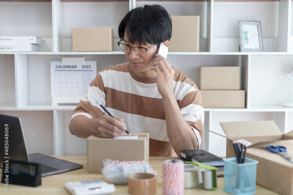 Asian man is taking online orders from a phone and chatting with customers to confirm their order, Selling products online or doing freelance work at home, Working at home and owning businesses. Asian man is taking online orders from a phone and chatting with customers to confirm their order, Selling products online or doing freelance work at home, Working at home and owning businesses.