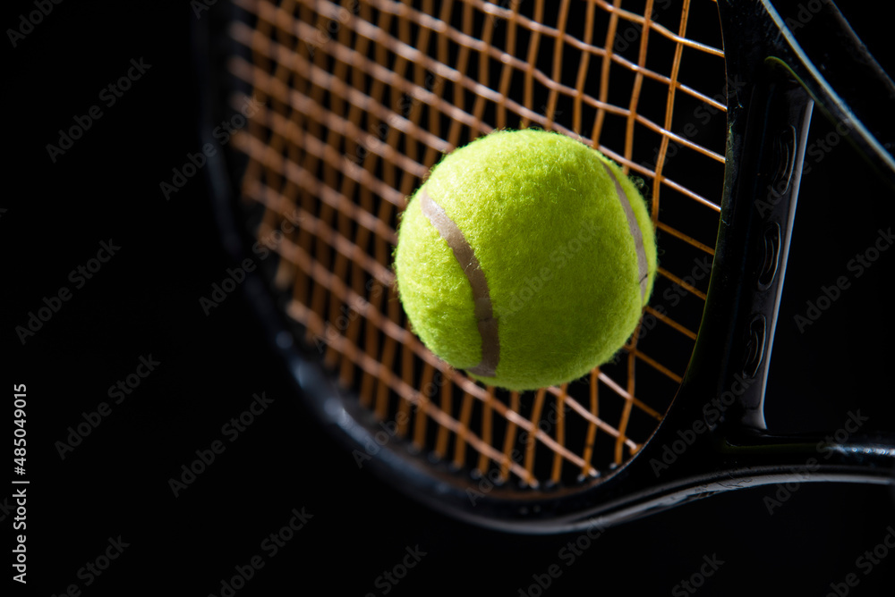 closeup tennis ball with racket on black background 