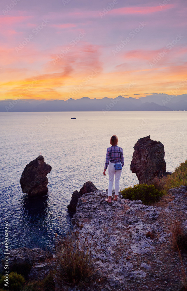 Tourism concept. Young traveling woman enjoying sunset sea view.