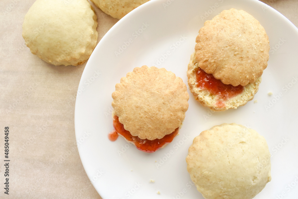 Scones with strawberry jam on a white plate. Flat lay top view photo. Food from above concept. Scones with strawberry jam on a white plate. Flat lay top view photo. Food from above concept.