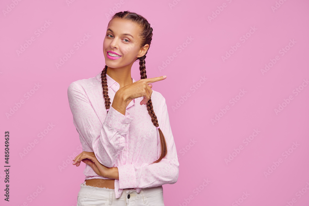 Your text here. Cheerful beautiful young woman pointing away while standing against pink background. Your text here. Cheerful beautiful young woman pointing away while standing against pink background.