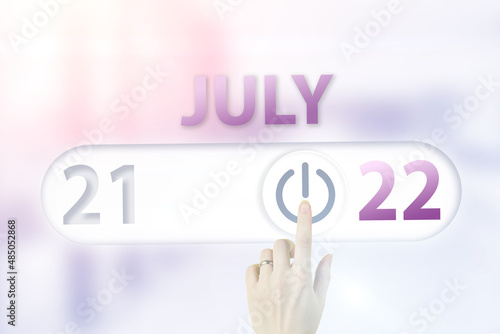 July 22nd. Day 22 of month, Calendar date.Hand finger switches pointing calendar date on sunlight office background. Summer month, day of the year concept.