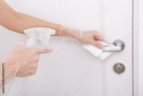 Cleaning door handles with wet wipe and white gloves. Woman hand using towel for cleaning home room door link. Sanitize surfaces prevention in hospital and public spaces against corona virus