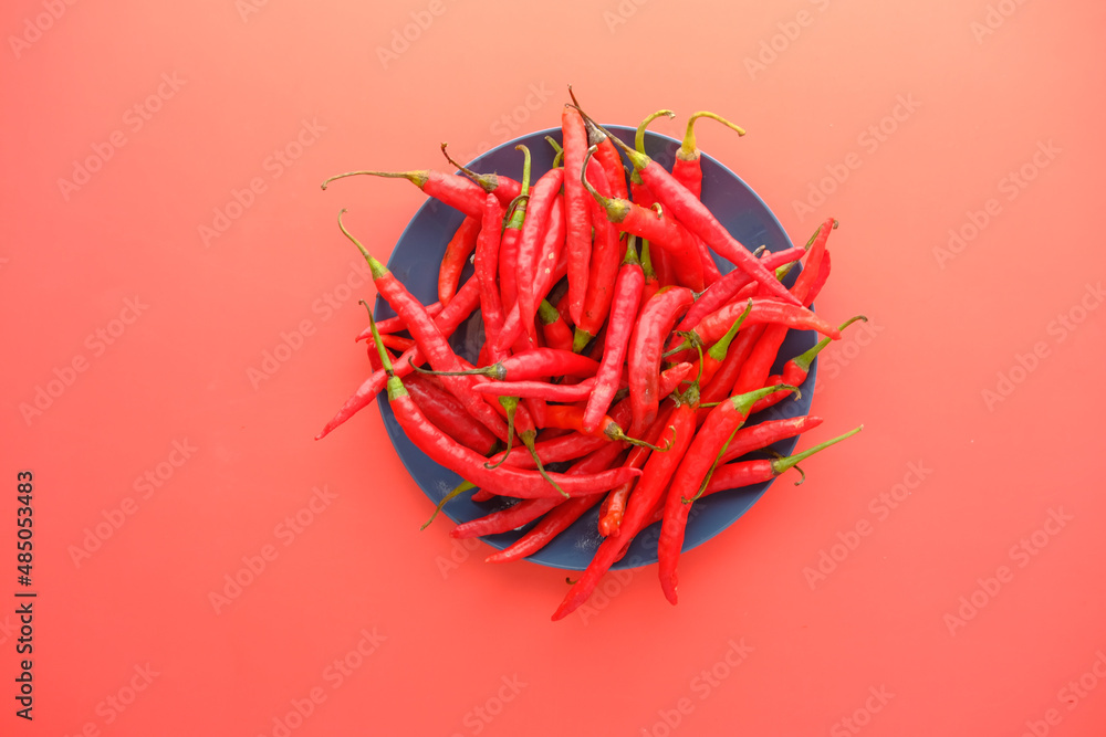 Fototapeta premium red chili pepper on a plate on red background 