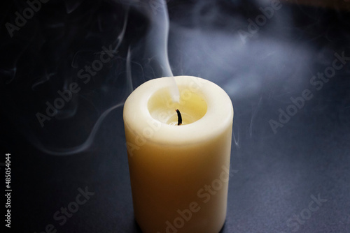 Photo of smouldering white candle on black background