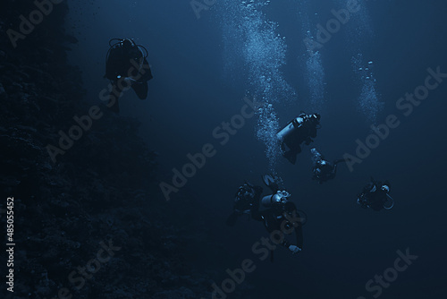 Foto divers underwater at depth in the blue sea background