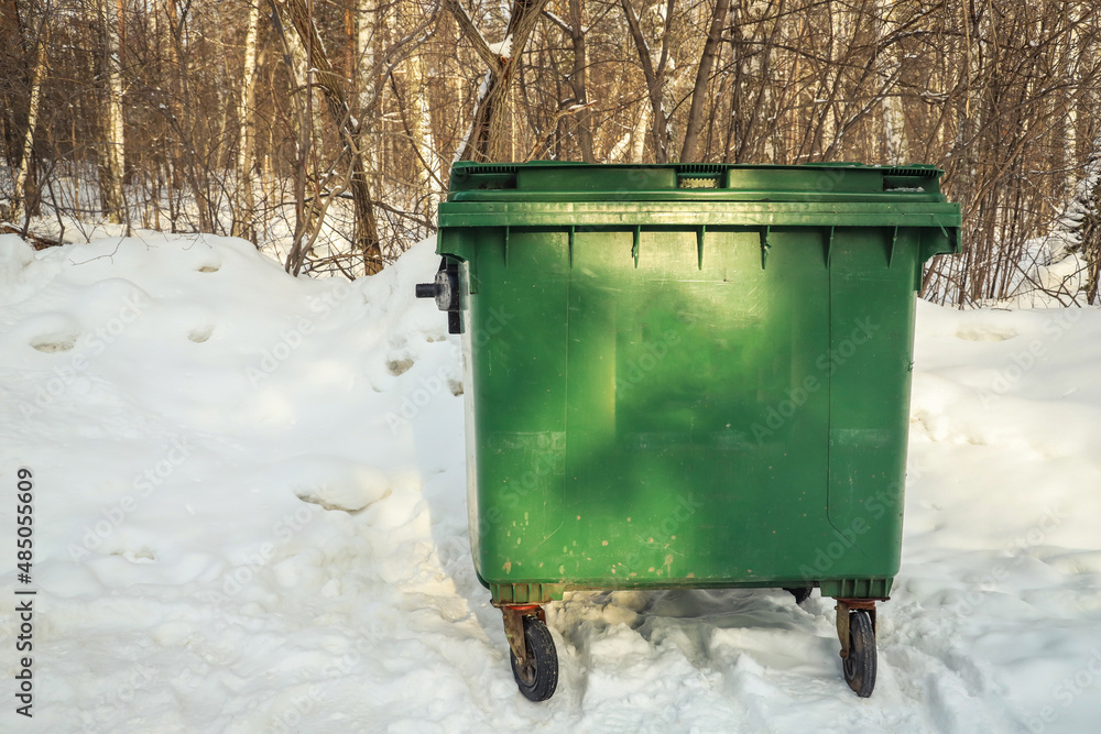 One green garbage can in with snow on top in winter. Outdoors One green garbage can in with snow on top in winter. Outdoors