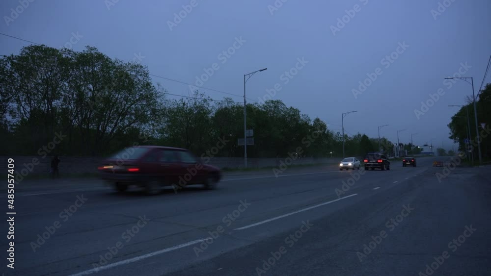 Cars with headlights on drive down a dark street outside the city Cars with headlights on drive down a dark street outside the city