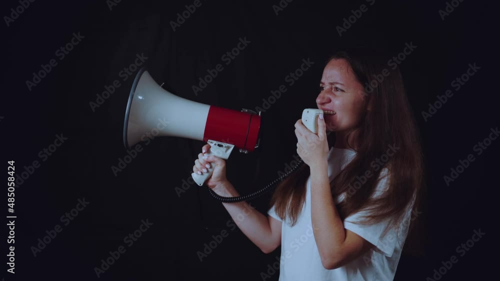 The girl speaks into a megaphone, black background The girl speaks into a megaphone, black background
