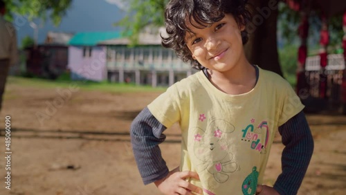 A shot of a small cute Asian Indian little rural girl in a rural village or countryside looking at the camera smiling.