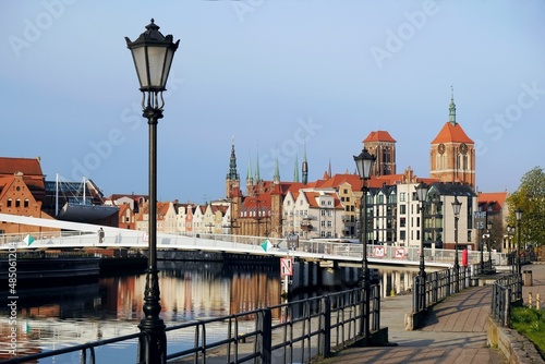 Promenade over Motlawa canal with vintage street lamps. In background, panorama of Old Town of Gdansk. Poland