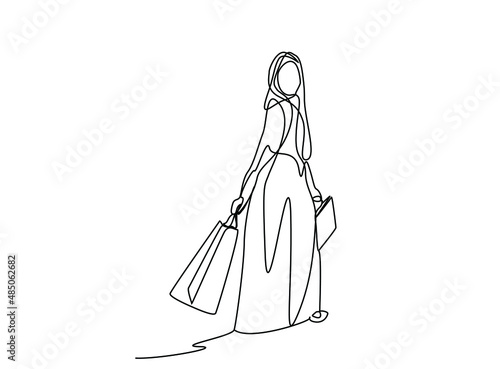 happy woman in muslim dress walking with shopping bags in hands