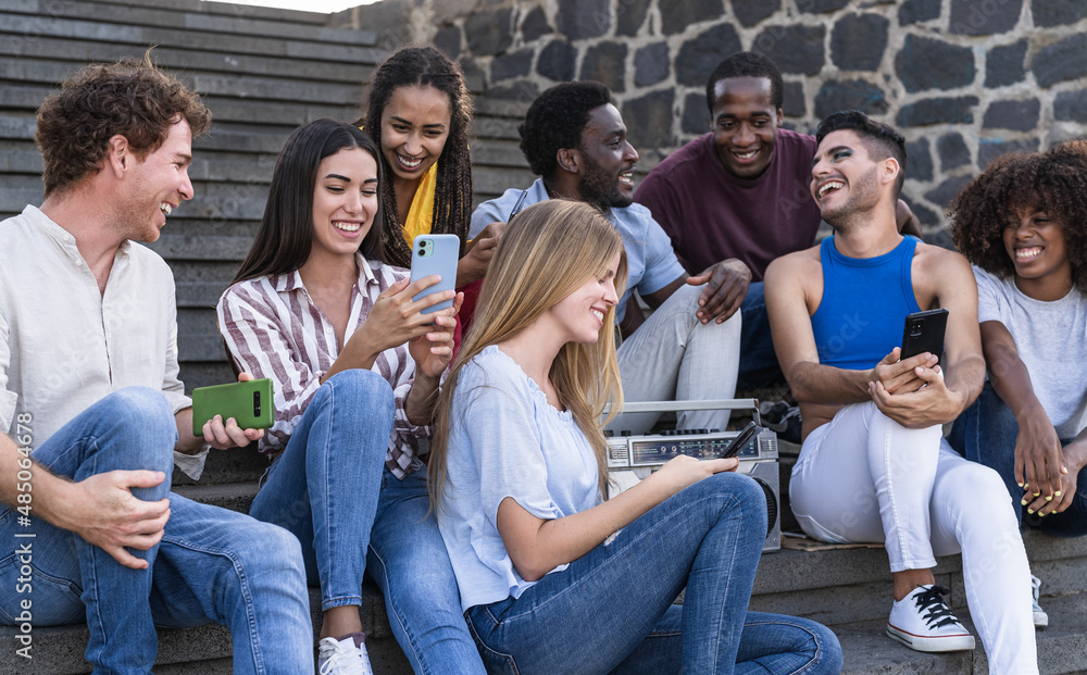 Obraz premium Young multiracial friends having fun using phone and listening music with boombox stereo outdoor - Youth millennial lifestyle concept