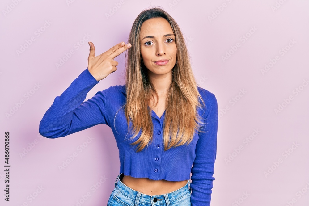 Beautiful hispanic woman wearing casual blue shirt shooting and killing oneself pointing hand and fingers to head like gun, suicide gesture. Beautiful hispanic woman wearing casual blue shirt shooting and killing oneself pointing hand and fingers to head like gun, suicide gesture.