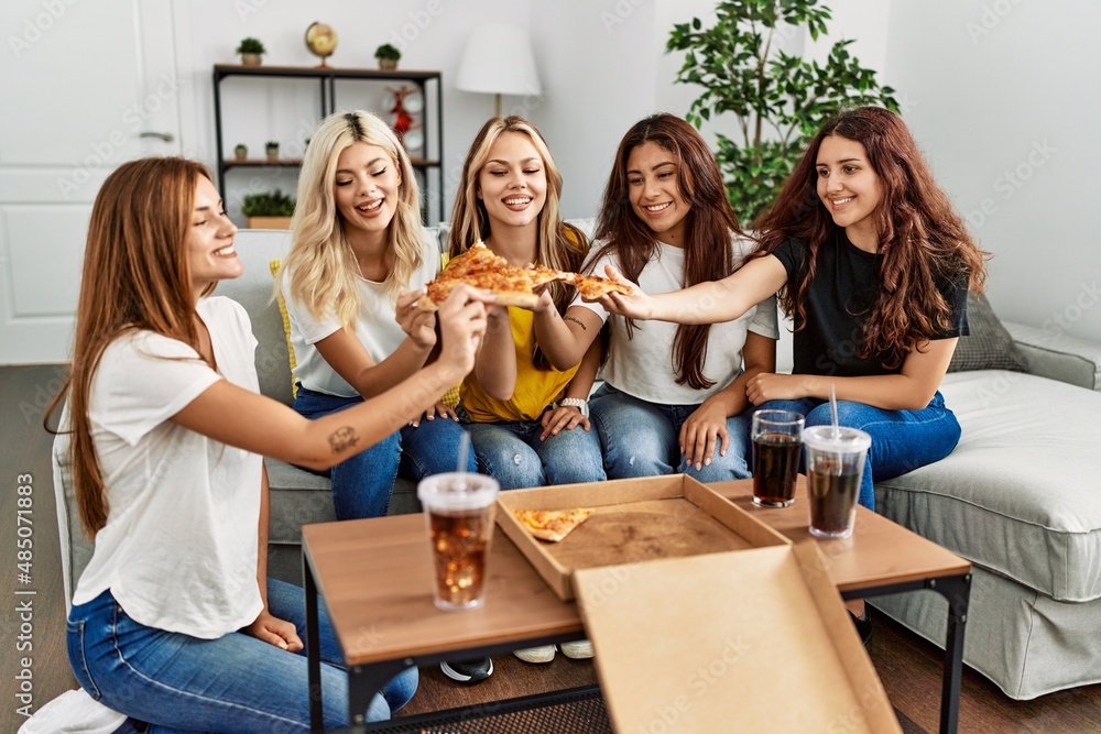 Obraz premium Group of young woman friends smiling happy eating pizza at home.