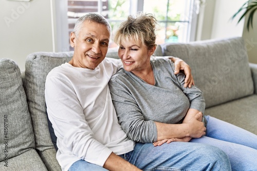 Senior caucasian couple smiling happy and hugging sitting on the sofa at home.