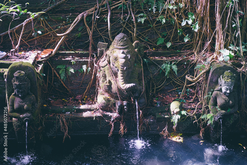 Asian art and religion. Balinese stono sculptures of Ganesha God near pond in jungle. Asian art and religion. Balinese stono sculptures of Ganesha God near pond in jungle.