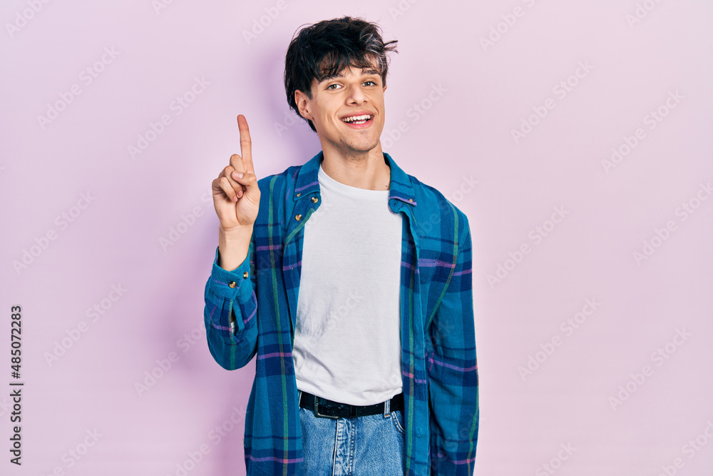 Handsome hipster young man wearing casual white t shirt and vintage shirt showing and pointing up with finger number one while smiling confident and happy. Handsome hipster young man wearing casual white t shirt and vintage shirt showing and pointing up with finger number one while smiling confident and happy.