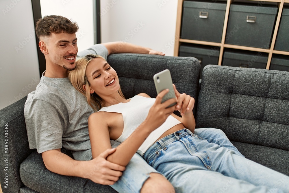 Young caucasian couple smiling happy using smartphone at home. Young caucasian couple smiling happy using smartphone at home.