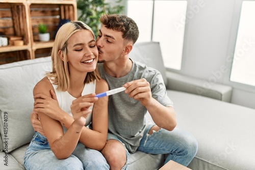 Young caucasian couple smiling happy holding pregnacy test at home. photo