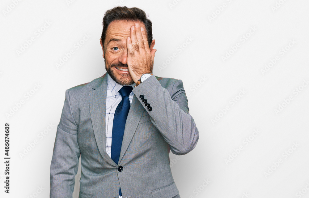 Middle age man wearing business clothes covering one eye with hand, confident smile on face and surprise emotion. Middle age man wearing business clothes covering one eye with hand, confident smile on face and surprise emotion.