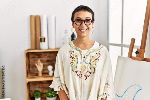 Tableau sur toile Young hispanic woman with short hair at art studio with a happy and cool smile on face