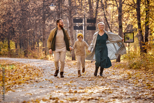 Excited caucasian family running, having fun in the park, autumn season, sunny day. cheerful positive spend vactions holidays on fresh air, smiling and laughing. family, children, love, emotions photo