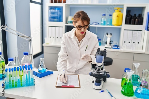 Young caucasian woman wearing scientist uniform    holding test tube at laboratory