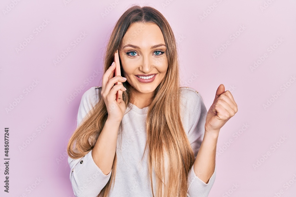 Young blonde girl having conversation talking on the smartphone screaming proud, celebrating victory and success very excited with raised arm Young blonde girl having conversation talking on the smartphone screaming proud, celebrating victory and success very excited with raised arm