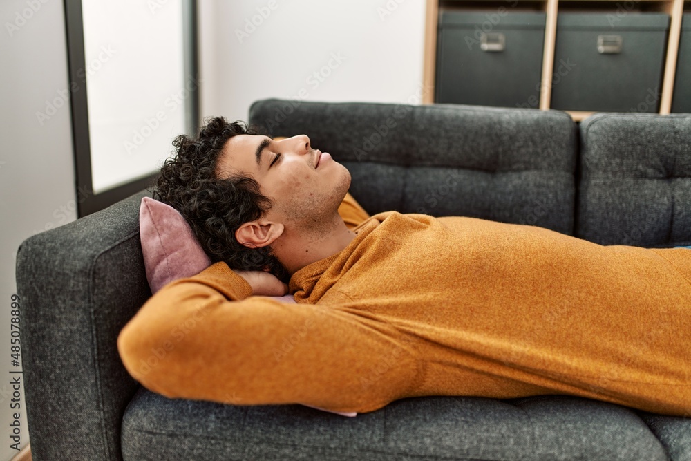 Young hispanic man smiling happy lying on the sofa at home. Young hispanic man smiling happy lying on the sofa at home.