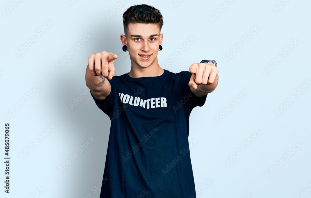 Fototapeta premium Young caucasian boy with ears dilation wearing volunteer t shirt pointing to you and the camera with fingers, smiling positive and cheerful