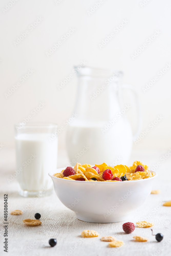 bowl of corn granola with milk, fresh raspberries, blueberries . milk in a jug and a glass on white wooden board for healthy breakfast bowl of corn granola with milk, fresh raspberries, blueberries . milk in a jug and a glass on white wooden board for healthy breakfast