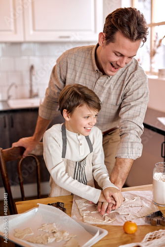 happy family in bright interior kitchen. Father and child son baking cookies, christmas celebration. handsome caucasian adult male looking at process of making tasty delicious cookies by son