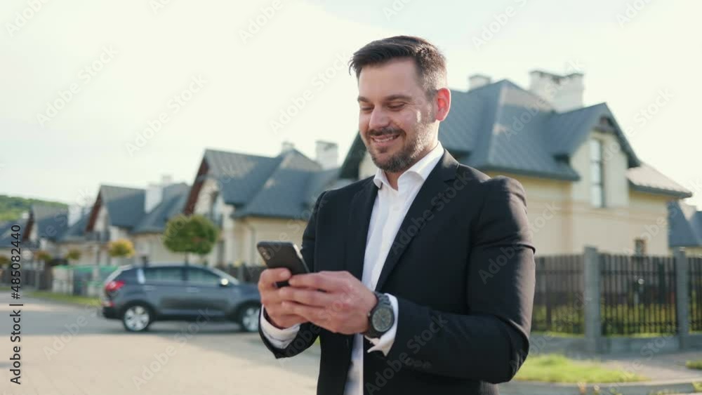 Confident young businessman using smartphone outside. Good-looking male boss in formal suit scrolling news feed, texting messages. Technologies, gadgets concept Confident young businessman using smartphone outside. Good-looking male boss in formal suit scrolling news feed, texting messages. Technologies, gadgets concept
