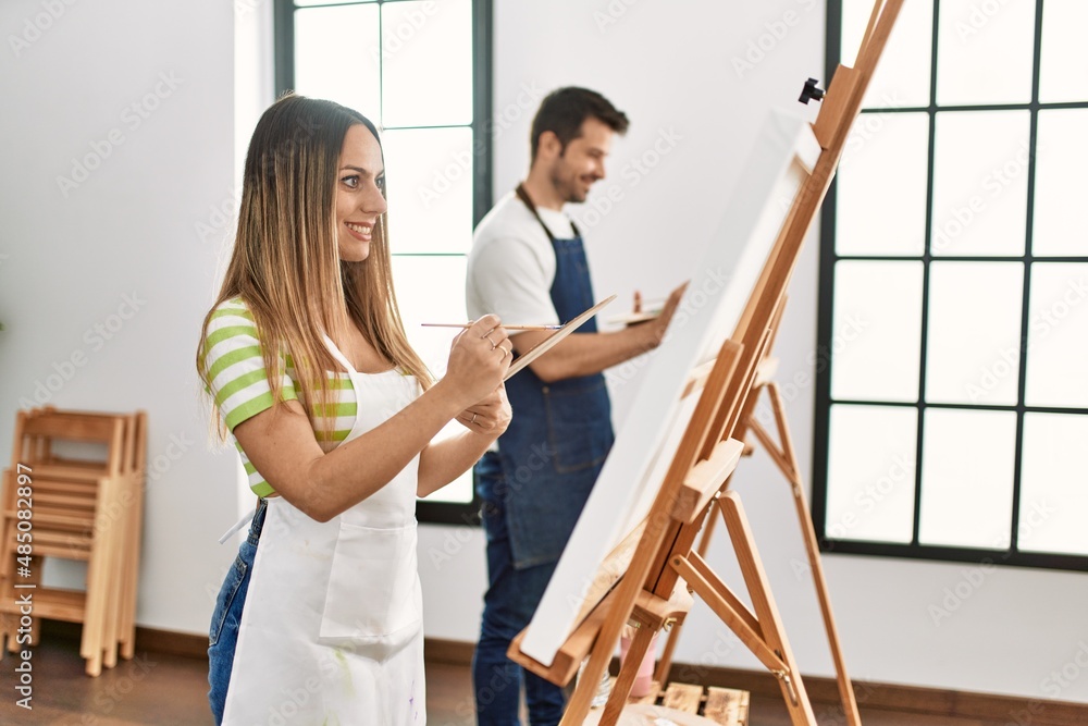 Two hispanic students smiling happy painting at art studio.
