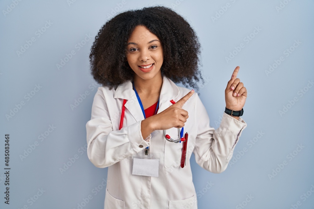 Young african american woman wearing doctor uniform and stethoscope smiling and looking at the camera pointing with two hands and fingers to the side. Young african american woman wearing doctor uniform and stethoscope smiling and looking at the camera pointing with two hands and fingers to the side.