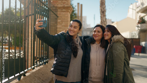 Mother and daugthers making selfie by the smartphone standing together at street