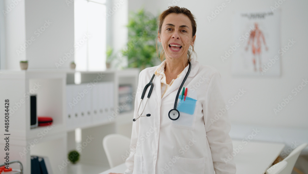 Middle age hispanic woman wearing doctor uniform standing at clinic Middle age hispanic woman wearing doctor uniform standing at clinic