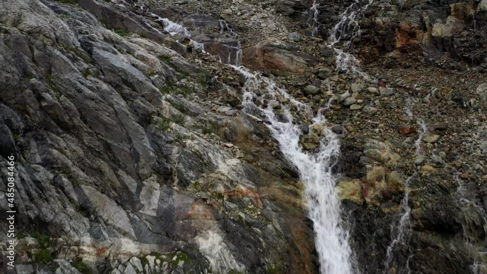 The cascade waterfall over rocky rugged mountain slope. Rough river stream The cascade waterfall over rocky rugged mountain slope. Rough river stream