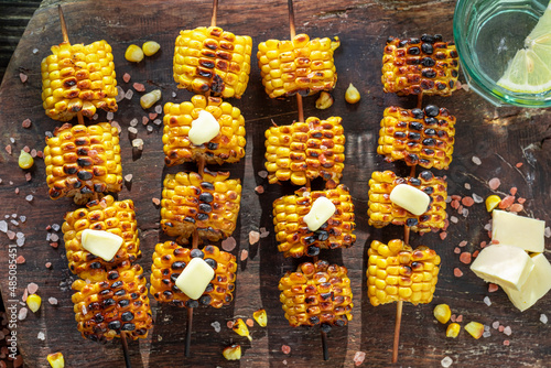 Homemade grilled corn cob on stick roast on bonfire.
