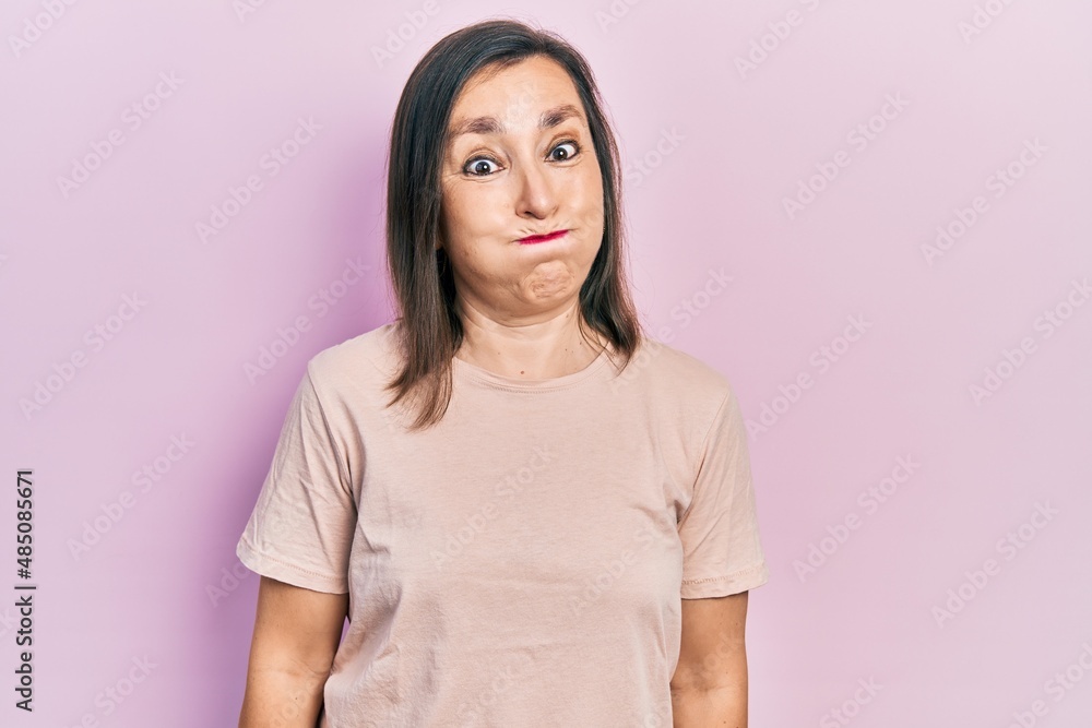 Middle age hispanic woman wearing casual clothes puffing cheeks with funny face. mouth inflated with air, crazy expression. Middle age hispanic woman wearing casual clothes puffing cheeks with funny face. mouth inflated with air, crazy expression.