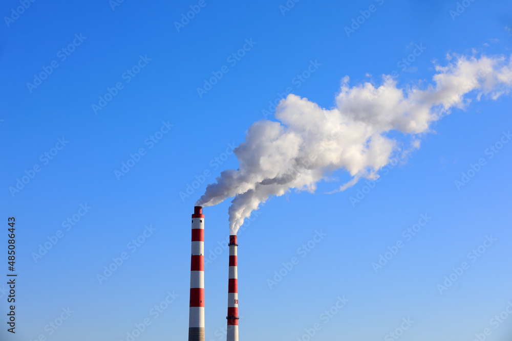 The chimney that emits smoke and dust in the blue sky The chimney that emits smoke and dust in the blue sky
