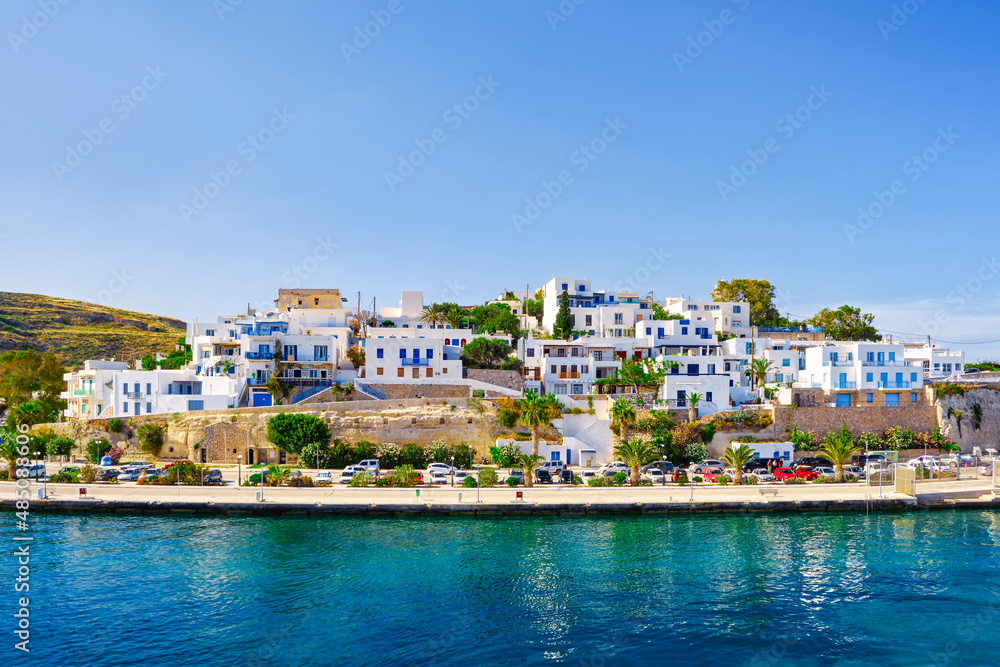 Beautiful summer day, sunshine in typical marina of Greek island. Whitewashed houses by waterfront. Mediterranean vacations. Milos, Cyclades, Greece.