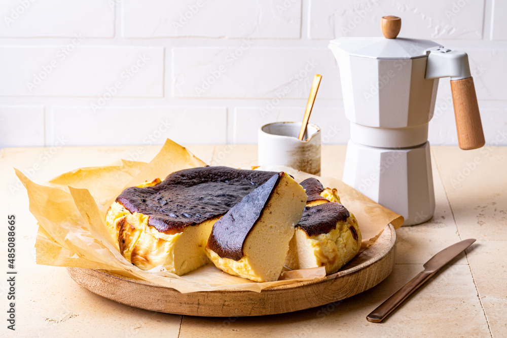 Fototapeta premium San Sebastian Basque Burnt Cheesecake. Basque burnt cheesecake on baking paper over wooden tray