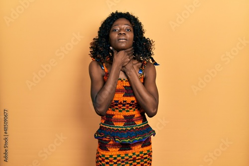 Young african american woman wearing traditional african clothes shouting and suffocate because painful strangle. health problem. asphyxiate and suicide concept.